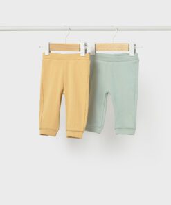 Two pastel baby pants on a rack yellow and mint green with wooden hangers