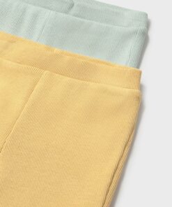Two folded corduroy pants in mint green and pale yellow shown from a close up angle to highlight the fabric texture