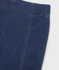 Close up of dark blue denim jeans showing the waistband seam and pocket edge on the right side of the image