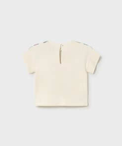 Cream-colored short-sleeve children's top with a back keyhole button opening and pastel shoulder accents.