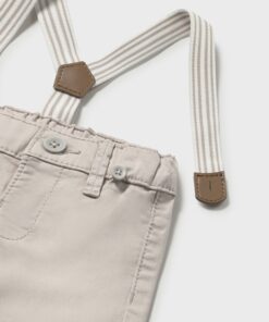 Beige pants with an elastic waistband and two white buttons paired with striped beige and white suspenders attached to leather patches
