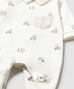 Cream baby onesie with small teddy bear on bicycles print, striped pocket, and snap closures at the bottom.