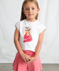 Young girl standing in front of a white backdrop wearing a white T shirt with a pink dress illustration and pink shorts