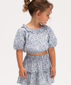 Young girl wearing a matching blue floral two piece outfit a smocked crop top with puff sleeves and a ruffled hem skirt