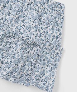 Close up of blue floral printed fabric with shirred elastic panels a gathered garment