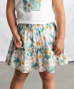 Child wearing a white top with a bag graphic and a teal and white daisy patterned skirt with yellow centers