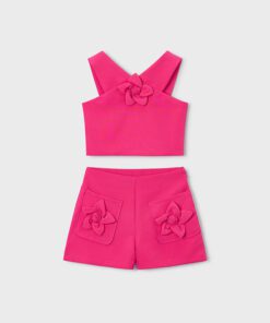 Bright pink two piece girls outfit sleeveless crop top with a fabric flower and matching pink shorts with flower appliques on pockets