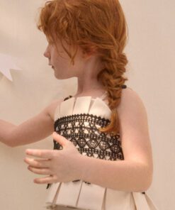 Side profile of a young girl with red braided hair wearing a white dress with black lace bodice detail
