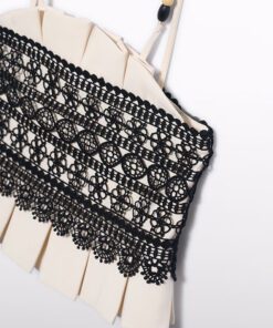 Beige garment with an intricate black lace panel across the front and a beaded strap