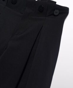 Close up of black dress pants waistband with buttons and front pleats visible at the waist area